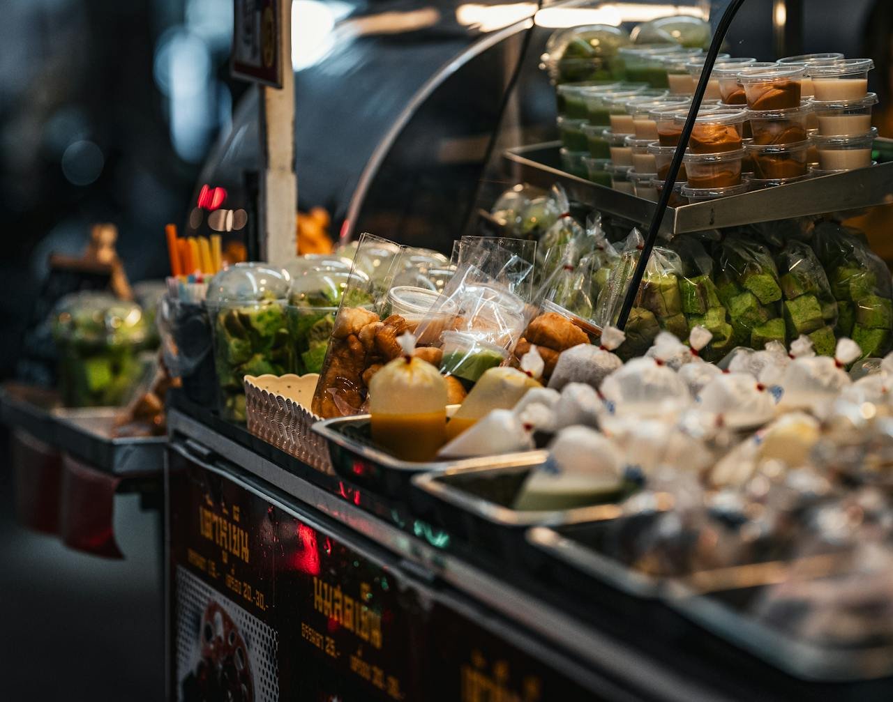Vibrant Thai street food stall showcasing an array of traditional snacks and desserts.